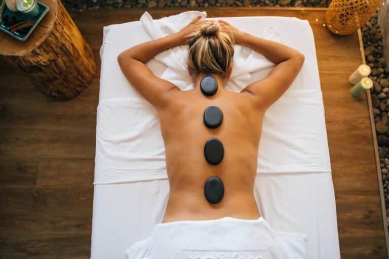 Person relaxing on a massage table during a hot stone massage treatment